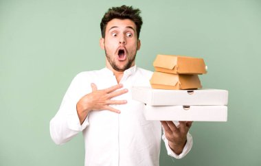 Fast food ile izole edilmiş genç yakışıklı adam kutuları taklit ediyor. teslimat ve paket konsepti