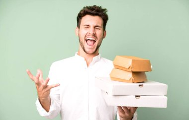 Fast food ile izole edilmiş genç yakışıklı adam kutuları taklit ediyor. teslimat ve paket konsepti