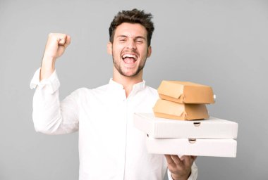 Fast food ile izole edilmiş genç yakışıklı adam kutuları taklit ediyor. teslimat ve paket konsepti