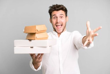 Fast food ile izole edilmiş genç yakışıklı adam kutuları taklit ediyor. teslimat ve paket konsepti