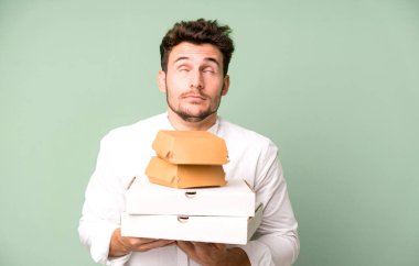 Fast food ile izole edilmiş genç yakışıklı adam kutuları taklit ediyor. teslimat ve paket konsepti