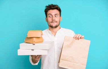 Fast food ile izole edilmiş genç yakışıklı adam kutuları taklit ediyor. teslimat ve paket konsepti