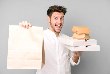 Fast food ile izole edilmiş genç yakışıklı adam kutuları taklit ediyor. teslimat ve paket konsepti