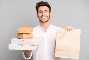 Fast food ile izole edilmiş genç yakışıklı adam kutuları taklit ediyor. teslimat ve paket konsepti