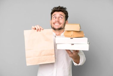 Fast food ile izole edilmiş genç yakışıklı adam kutuları taklit ediyor. teslimat ve paket konsepti