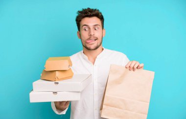 Fast food ile izole edilmiş genç yakışıklı adam kutuları taklit ediyor. teslimat ve paket konsepti