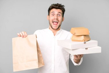 Fast food ile izole edilmiş genç yakışıklı adam kutuları taklit ediyor. teslimat ve paket konsepti