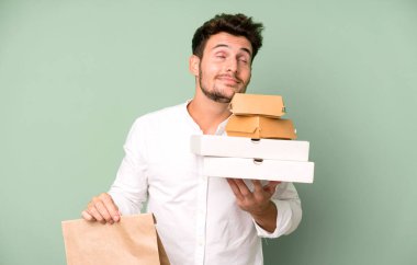Fast food ile izole edilmiş genç yakışıklı adam kutuları taklit ediyor. teslimat ve paket konsepti