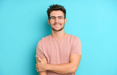 Genç yakışıklı adam utangaç ve neşeli bir şekilde gülüyor, arkadaş canlısı ve olumlu ama güvensiz bir tavırla.