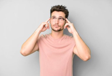 Genç ve yakışıklı bir adam kafası karışmış ya da şüphe içinde, bir fikre odaklanmış, çok düşünüyor, kenarda boşluğu kopyalamaya çalışıyor.