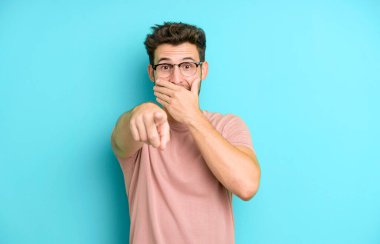 Genç yakışıklı adam sana gülüyor, kamerayı işaret ediyor ve seninle dalga geçiyor ya da alay ediyor.