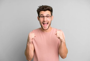 Genç yakışıklı adam şok olmuş, heyecanlı ve mutlu, gülüyor ve başarıyı kutluyor, vay canına diyor.!