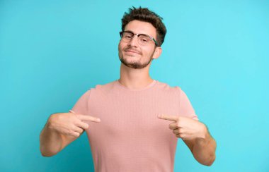 Genç yakışıklı adam gururlu, kibirli, mutlu, şaşırmış ve tatmin olmuş görünüyor, kendini gösteriyor, kazanan gibi hissediyor.