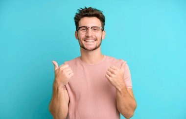 Genç ve yakışıklı adam neşeyle gülümsüyor ve mutlu görünüyor, kaygısız ve pozitif hissediyor.