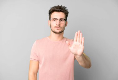 Genç ve yakışıklı adam ciddi, sert, hoşnutsuz ve kızgın görünüyor.