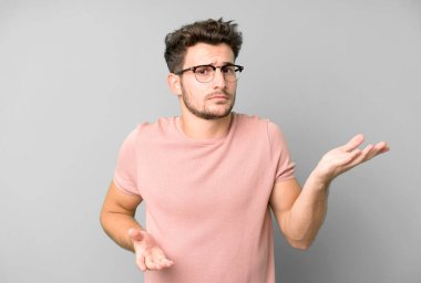 Şaşkın, şaşkın ve stresli görünen genç bir adam. Farklı seçenekler arasında merak ediyor. Belirsiz hissediyor.