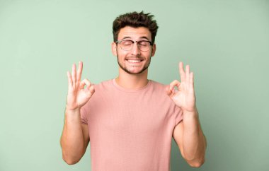 Genç yakışıklı adam konsantre olmuş ve meditasyon yapıyor, kendini tatmin olmuş ve rahatlamış hissediyor, düşünüyor ya da bir seçim yapıyor.