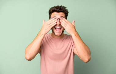 Genç yakışıklı adam gülümsüyor ve mutlu hissediyor, iki eliyle gözlerini kapatıyor ve inanılmaz bir sürpriz bekliyor.