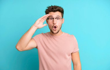 Genç yakışıklı adam mutlu, şaşkın ve şaşırmış görünüyor, gülümsüyor ve inanılmaz ve inanılmaz iyi haberleri fark ediyor.