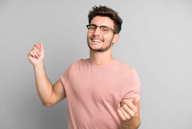 Genç yakışıklı adam gülümsüyor, kaygısız hissediyor, rahat ve mutlu, dans ediyor ve müzik dinliyor, bir partide eğleniyor.