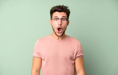 Genç ve yakışıklı bir adam şok olmuş ya da şaşırmış görünüyor, ağzı açık bir şekilde 