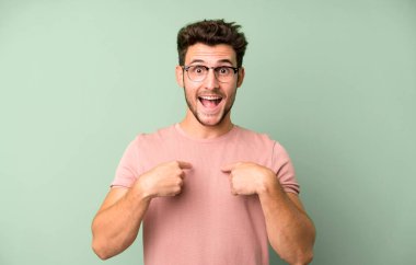 Genç yakışıklı adam mutlu, şaşkın ve gururlu, heyecanlı, şaşkın bakışlarıyla kendini işaret ediyor.