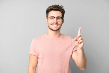 Genç yakışıklı adam gülümsüyor ve arkadaş canlısı görünüyor, bir numara ya da ilk eli önde, geriye doğru sayıyor.