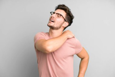 Genç yakışıklı adam yorgun, stresli, endişeli, hayal kırıklığına uğramış ve depresyonda, sırtı ya da boynu ağrıyan