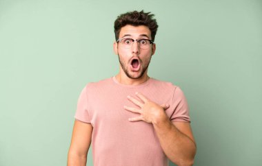 Genç yakışıklı adam şaşkın, şaşkın ve şaşırmış hissediyor, elleri göğsünde ve ağzı açık, kim diyor, ben mi??