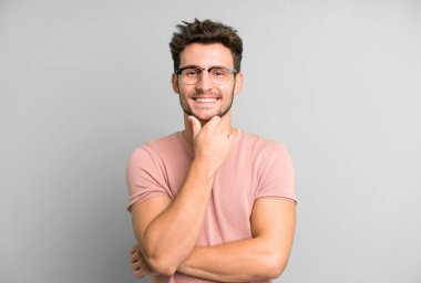 Genç yakışıklı adam gülümsüyor, hayattan zevk alıyor, mutlu, arkadaş canlısı, tatmin olmuş ve tasasız.