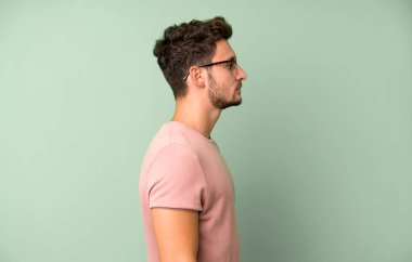 Profil görünümündeki genç yakışıklı adam ilerideki boşluğu kopyalamaya çalışıyor, düşünüyor, hayal ediyor ya da hayal kuruyor.