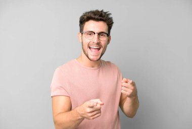 Genç yakışıklı adam kendini mutlu, havalı, tatmin olmuş, rahat ve başarılı hissediyor, kameraya bakıyor, seni seçiyor.