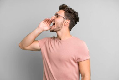 Genç yakışıklı profil görüntüsü, mutlu ve heyecanlı görünüyor, bağırıyor ve kenardaki boşluğu kopyalamak için arıyor