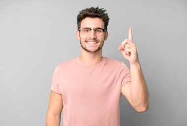 Genç yakışıklı adam neşeyle ve mutlulukla gülümsüyor, tek eliyle yukarıyı göstererek boşluğu kopyalıyor.