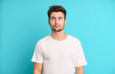 Genç ve yakışıklı adam kafası karışmış görünüyor, merak ediyor ya da bir sorunu çözmeye çalışıyor ya da düşünüyor.
