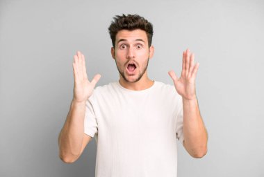 Genç yakışıklı adam şok olmuş ve şaşkın bakıyor, inanılmaz bir şey fark ettiğinde çenesi şaşkın şaşkın