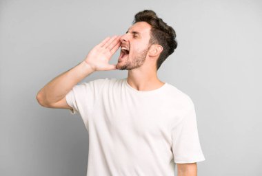 Genç yakışıklı adam öfkeyle bağırıyor kenardaki boşluğu kopyalasın diye, eli ağzının yanında.