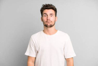 Genç ve yakışıklı adam şapşal ve komik görünüyor. Şaşı bakışlı, şakacı ve şakacı.