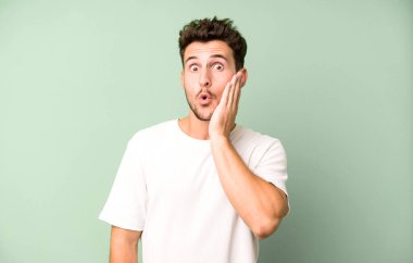 Genç yakışıklı adam şok olmuş ve ağzı açık halde yüz yüze inanamamaktan şaşkına dönmüş durumda.