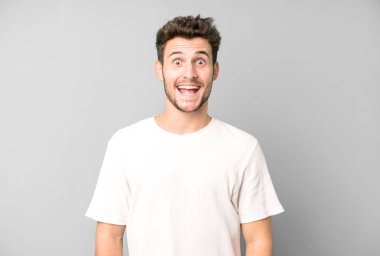 Genç yakışıklı adam mutlu ve hoş bir şekilde şaşırmış görünüyor. Büyülenmiş ve şok olmuş bir ifadeyle heyecanlanıyor.
