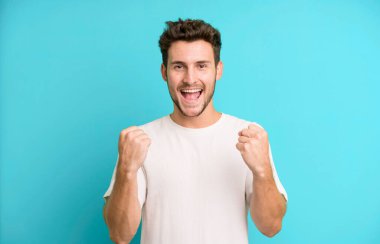 Genç yakışıklı adam zaferle bağırıyor, gülüyor, mutlu ve heyecanlı hissediyor başarıyı kutlarken.