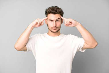 Ciddi ve konsantre görünümlü, beyin fırtınası yapan ve zorlu bir sorunu düşünen genç yakışıklı bir adam.