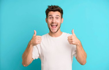 Genç yakışıklı adam gülümsüyor. Mutlu, pozitif, kendinden emin ve başarılı görünüyor.