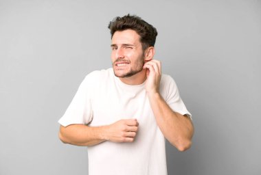 Genç ve yakışıklı bir adam stresli, hayal kırıklığına uğramış ve yorgun, endişeli ve sorunlu bir bakışla boynunu okşuyor.