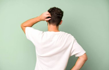 Genç yakışıklı bir adam bilgisiz ve kafası karışık hissediyor, bir çözüm düşünüyor, eli kalçasında, diğeri kafasında, dikiz aynasından.