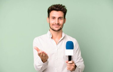 Yakışıklı genç mutlu bir şekilde gülümsüyor ve bir konsept sunuyor. Hem de mikrofonla. persenter konsepti