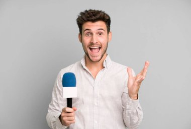 Yakışıklı genç kendini mutlu hissediyor ve inanılmaz bir şeye hayret ediyor. Hem de mikrofonla. persenter konsepti