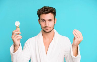 Yakışıklı genç kapiş ya da para hareketi yapıyor. Bornoz ve tıraş konseptiyle ödemeni söylüyor.