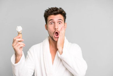 Yakışıklı genç şokta ve korkmuş bornoz giyiyor ve traş oluyor.