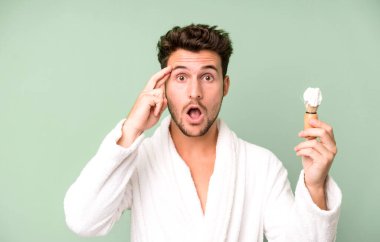 Yakışıklı genç şaşırmış görünüyor, yeni bir düşünce, fikir ya da konsept fark ediyor bornoz ve traş konsepti giyiyor.